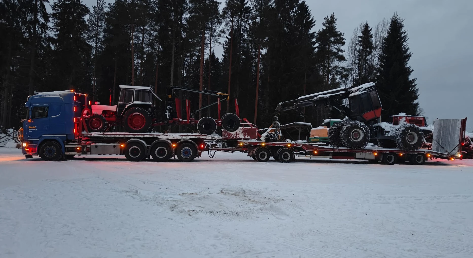Nehvonen Oy:n sininen lavettiauto kuljettaa kaivinkonetta työmaalla