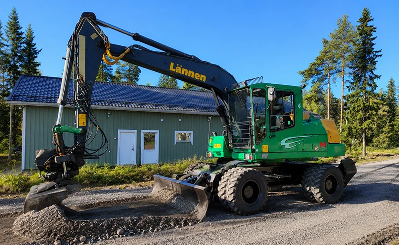 Traktori kunnostaa pihatietä metsäisessä ympäristössä