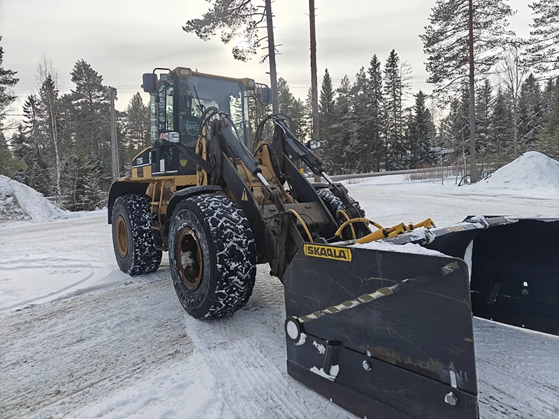 Traktori lumitöissä talvisessa pihassa